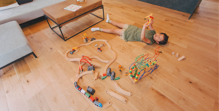 床の上でおもちゃを散らかして遊ぶ子ども
