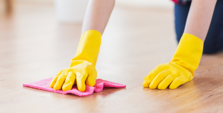 黄色い手袋をはめてピンク色の布巾で床を拭いている様子