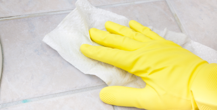 黄色いゴム手袋をはめて雑巾でタイルを清掃している様子