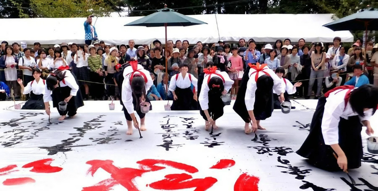 熊野町の筆祭りで巨大な和紙の上で文字を書いている女性達